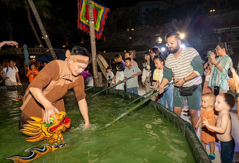 Du khách trải nghiệm điều khiển rối nước sau show diễn "Rối Việt - trẩy hội mùa xuân" tại khu du lịch thị trấn Hoàng Hôn, khu vực Nam đảo Phú Quốc. Ảnh: Trung Hiếu